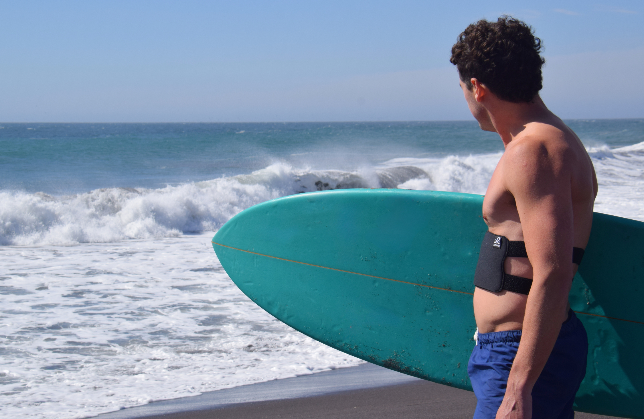 male surfing looking at the ocean wearing ribguard